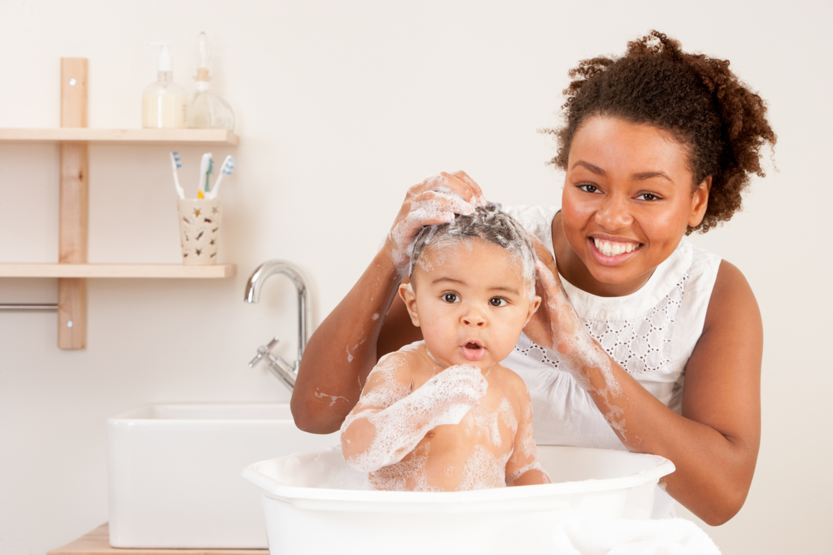 mulher lavando o cabelo do bebê e sorrindo