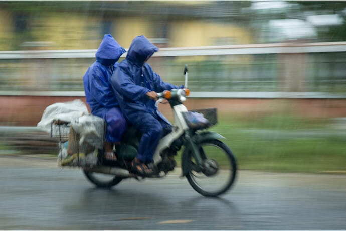 Senhor na moto com capa de chuva