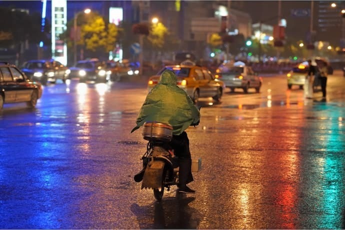 Motoqueiro na estrada com capa de chuva