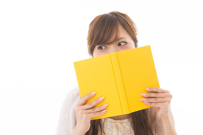 Mulher japonesa com um livro na mão cobrindo parte rosto
