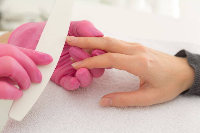 Manicure lixando as unhas de uma mulher
