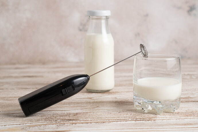 Espumador de leite, copo e jarra de vidro com leite