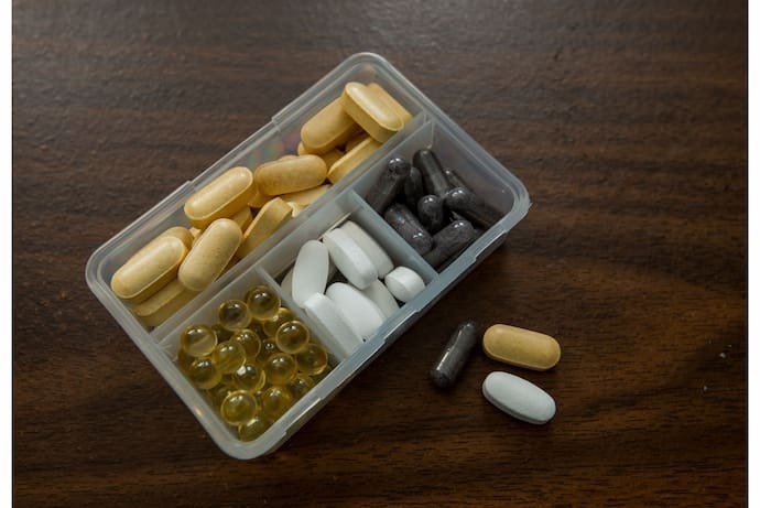Diferentes comprimidos e cápsulas de vitaminas organizadas em uma embalagem.