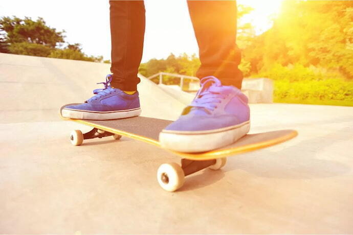 Pessoa com tênis azuis sobre um skate