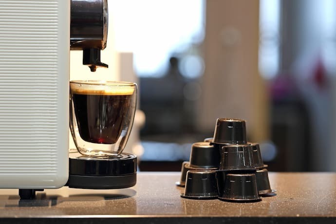 Cápsulas de café ao lado de máquina